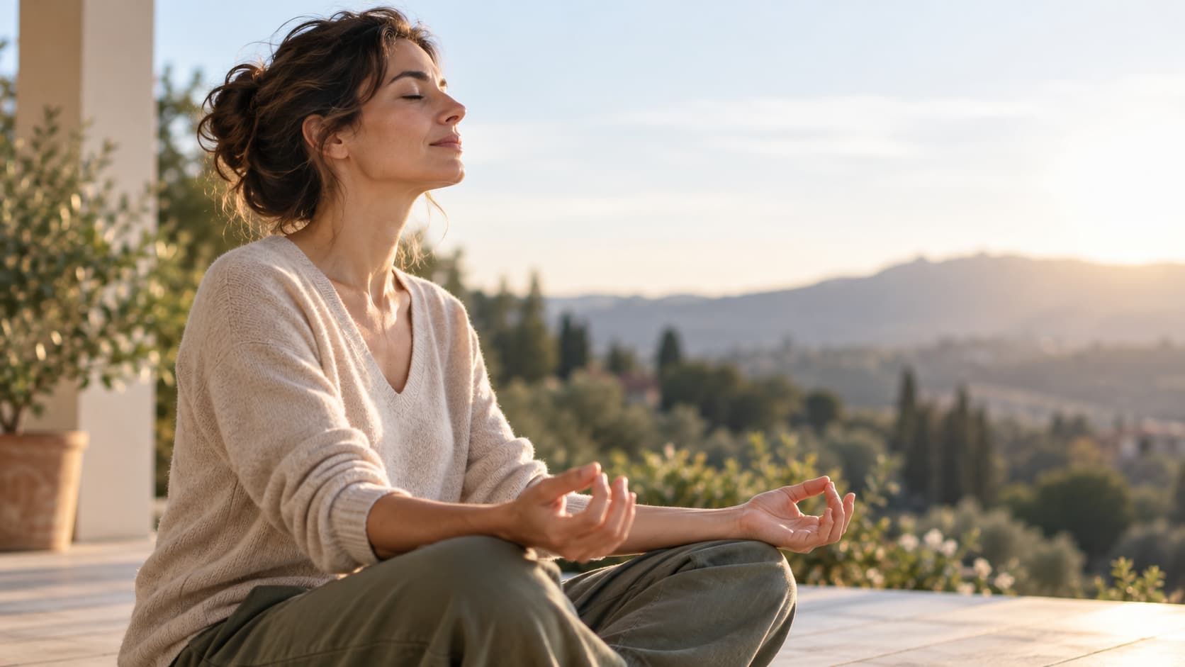 Una donna pratica la meditazione su una terrazza immersa nella natura. L'immagine rappresenta la mindfulness come pratica di attenzione e consapevolezza dell'esperienza presente.